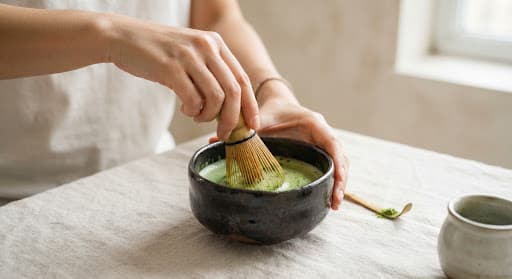 Whisking bright green ceremonial matcha in a ceramic bowl